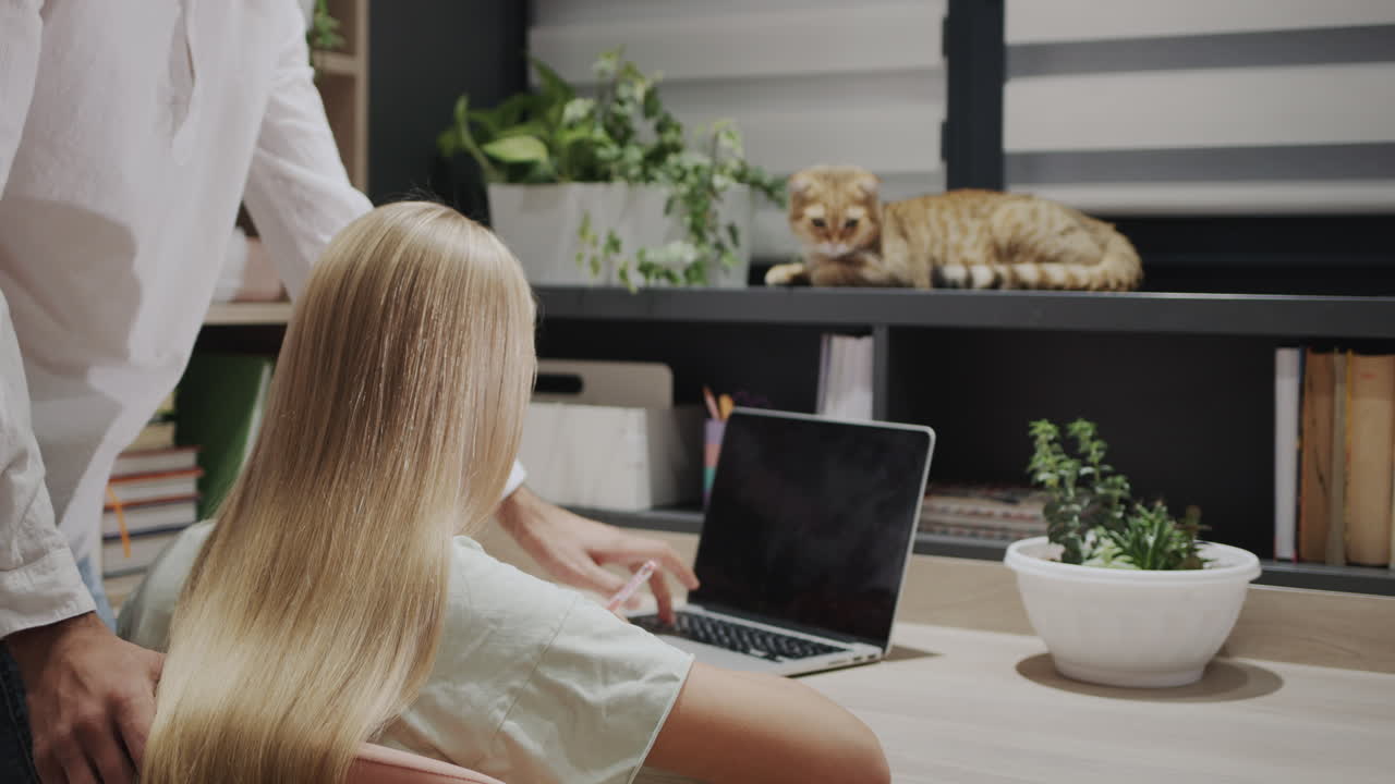 형은 여동생의 숙제를 도와주고, 고양이가 에 앉아서 집에서 공부합니다.