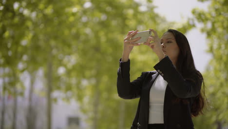 mujer joven enfocada tomando fotos con un teléfono inteligente