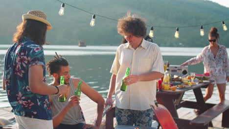 diverse men drinking beer and chatting at lake party