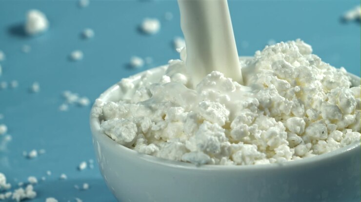 Movimento rallentato: latte versato su ricotta fresca in una ciotola bianca