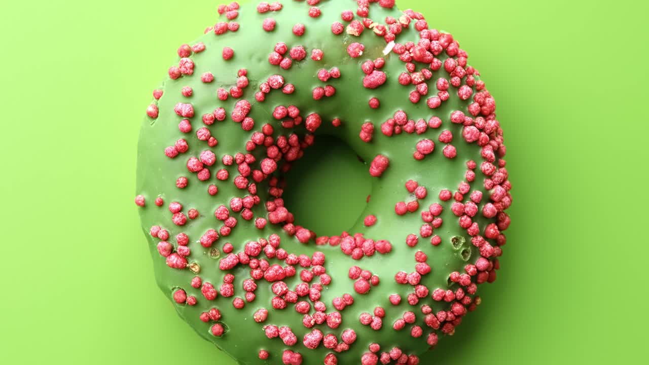 rosquilla de anillo de vidrio verde fresco cubierta por una cubierta de pastel rosa giratoria. filmada con cámara roja en 4k