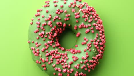 fresh green glazed ring donut covered by pink pastry topping rotating. shot with red camera in 4k