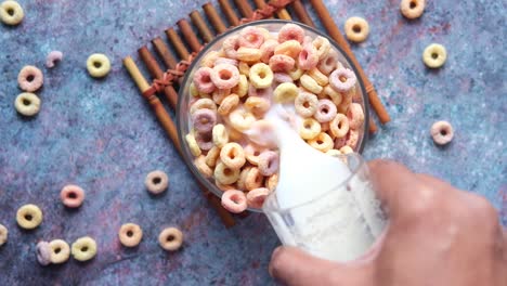 pouring milk into a bowl of colorful cereal