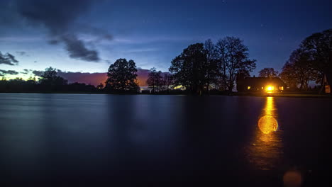 Erleben-Sie-Den-Atemberaubenden-Tag-zu-Nacht-Himmel-Mit-Sternen-Und-Hauslicht,-Das-Auf-Das-Wasser-Fällt