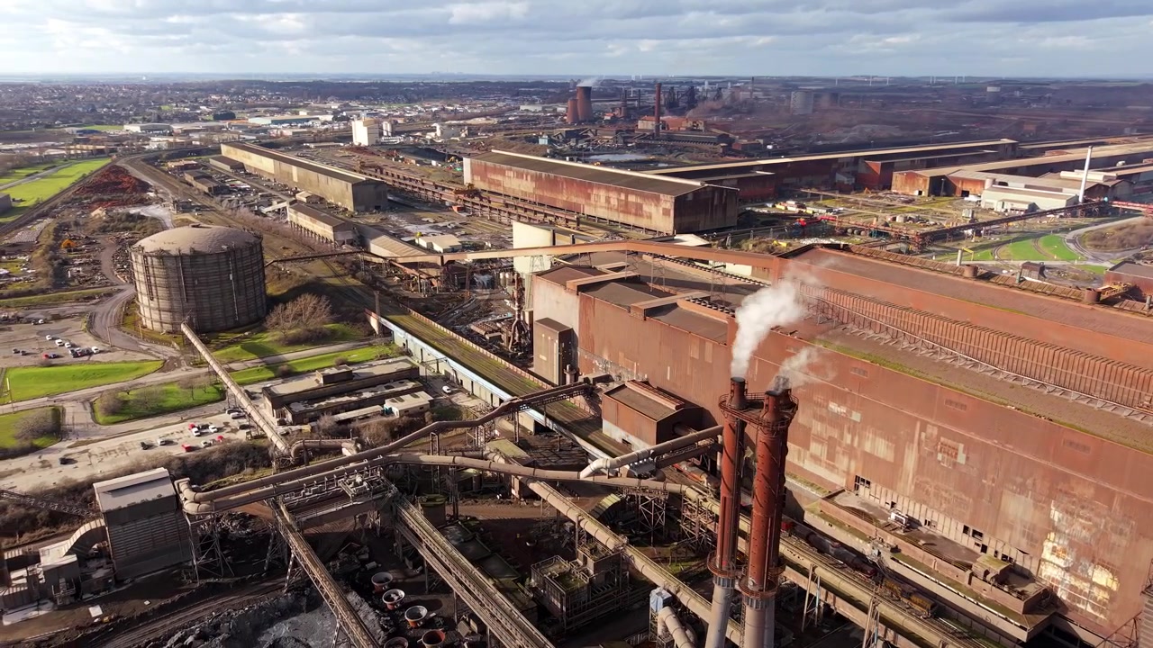 Drone shot flying over a massive industrial steel mill and heavy manufacturing coking facility in Scunthorpe, UK.