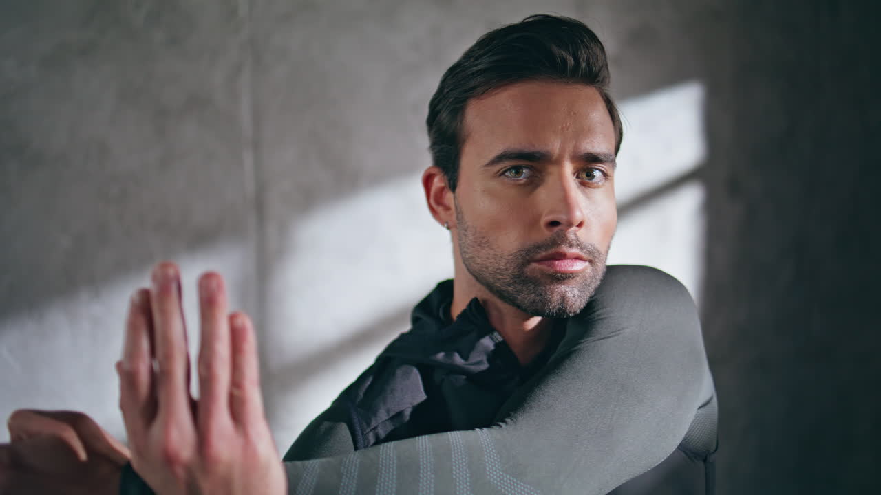 Strong athlete stretching hands at workout in gym closeup. Man looking camera
