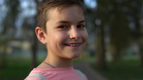 cute boy looking camera in spring garden. joyful guy in brackets posing outdoors