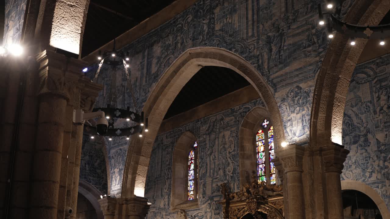 Interior of a Portuguese church with baroque arches, stained glass, and blue azulejo tile walls