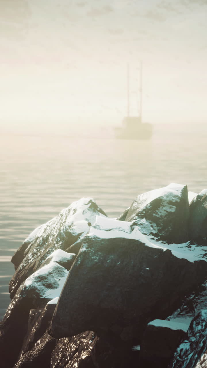 배 가 안개 가 가득 한 바다 를 가로질러 항해 하고 있으며, 앞면 에는 눈 으로 인 바위 들 이 있다