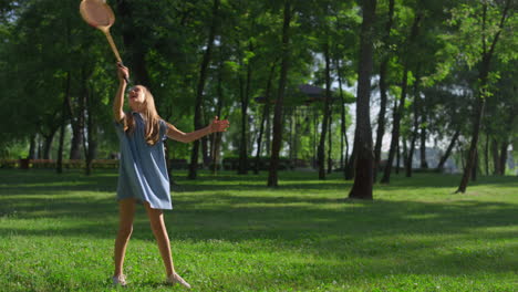 joyful little girl hit shuttlecock with racket in city park. family picnic time.