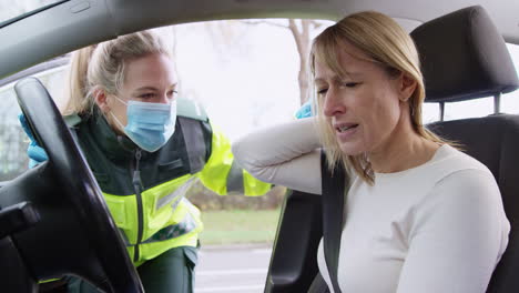 female paramedic helping female driver with whiplash neck injury involved in road traffic accident