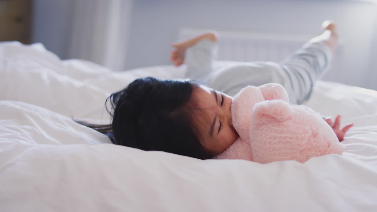 아버지 는 딸 과 그 의 부드러운 장난감 과 함께 집 에서 침대 에서 게임 을 하고 있다