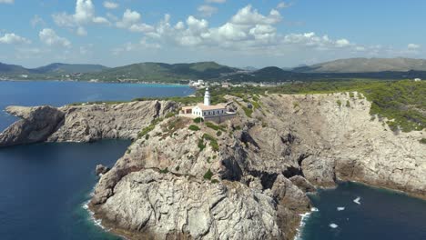 capdepera lighthouse on a headland overlooking the sea in majorca, aerial reveal