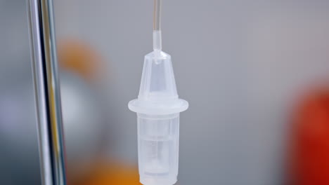 liquid medicines slowly dripping inside the reservoir of drop counter. medical equipment close up.