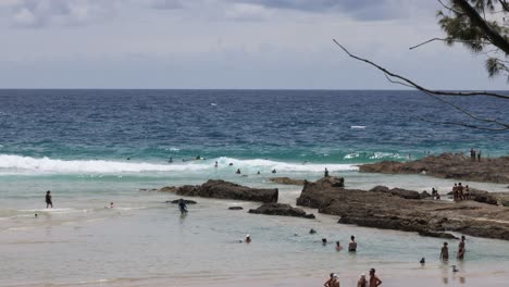 personas nadando y relajándose en una playa rocosa