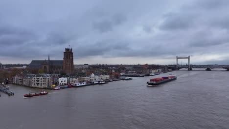 Picturesque-cityscape,-impressive-architecture,-container-vessel-sails-onward