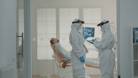 dental team of dentists consulting patient in cabinet