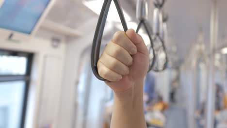 close-up of hands holding handrail or grip straps in metro train,public subway transportaion train