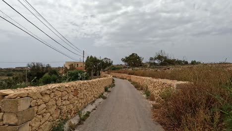 Driving-on-narrow-country-road-between-stone-walls,-first-person-view