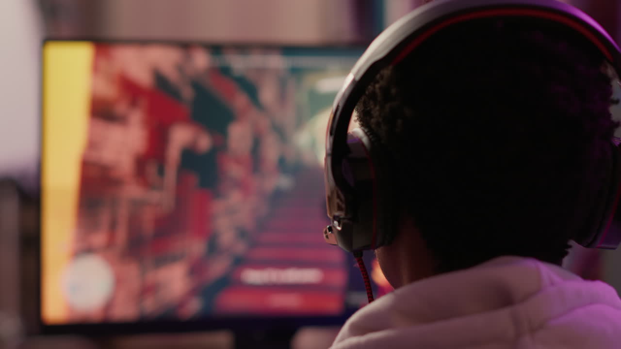 Overs shoulder closeup of gamer playing intense multiplayer action game in online competition talking with team