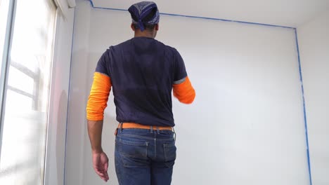 un hombre pinta la pared usando un pintor de rodillos - de cerca