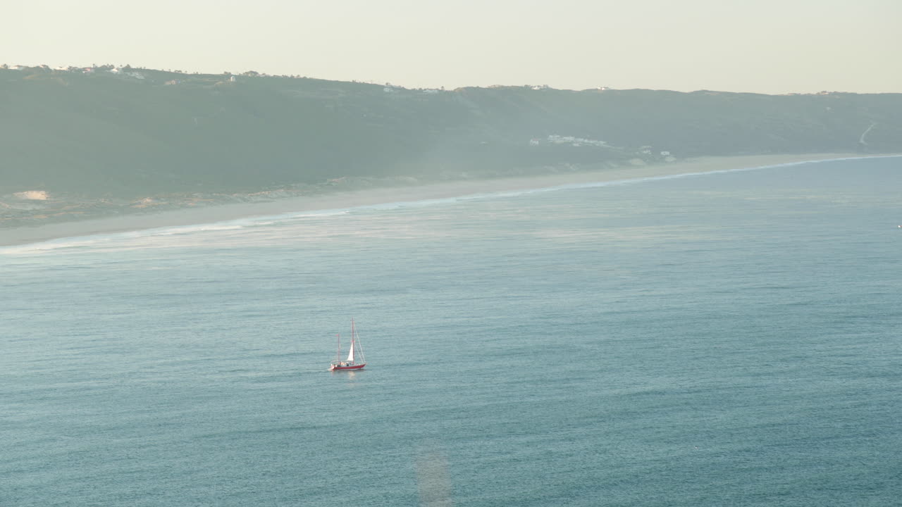 포르투갈 나자레 프라이아 두 노르테에서 안개 낀 일출 아침 동안 잔잔한 바다를 항해하는 보트