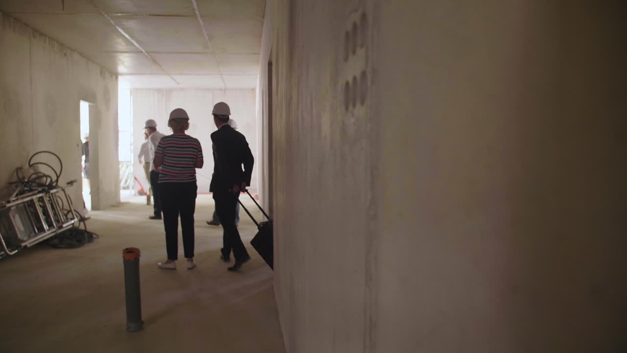 grupo de hombres y mujeres de negocios visitando un sitio de construcción con cascos