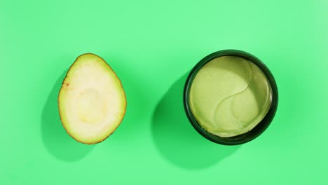 fresh ripe avocados with cream and essential oil on green background with mint mentol, make up cosmetics