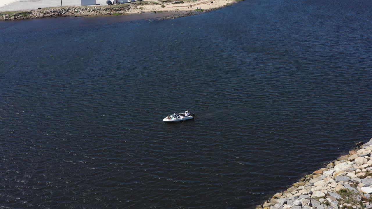 모터 보트 의 공중 사진 을 찍은 사람 들 이 천천히 강 입구 를 따라 항해 하고 있다