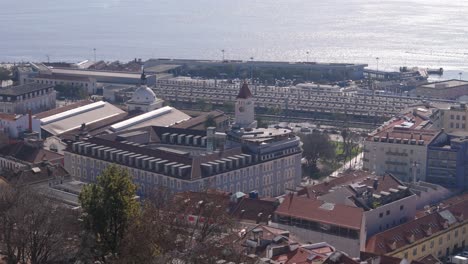 vista aérea de telefoto de la pared de la fachada azul con techo naranja y la torre del reloj en lisboa, portugal