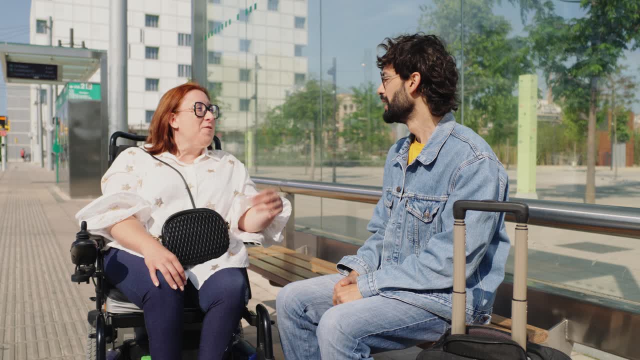 A woman in a wheelchair and a man talking at a train station
