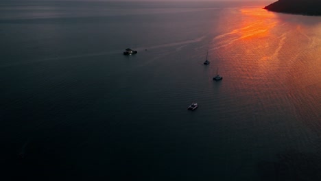 los barcos se desplazan ante una isla al atardecer