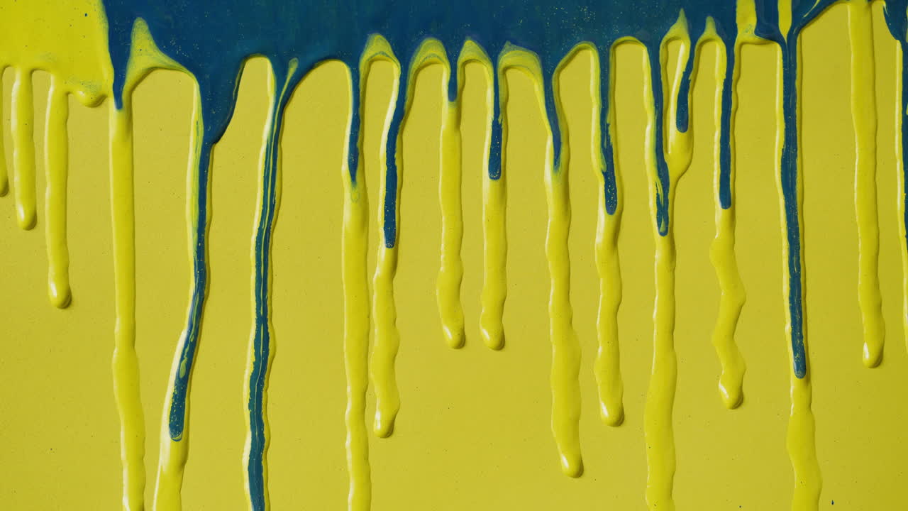 Pintura azul goteando sobre una superficie amarilla vibrante