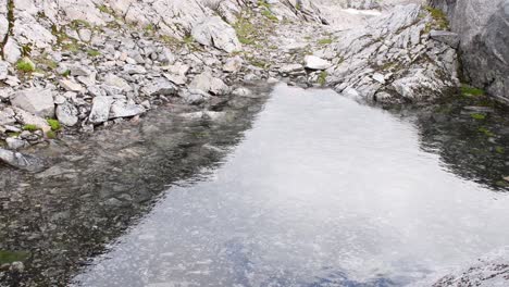 Close-up-shot-of-natural-stony-pond-with-reflection-of-sun-in-Norway