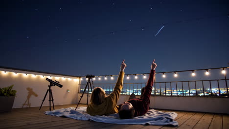 couple stargazing on a rooftop at night