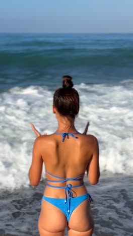 woman in blue bikini on a beach with waves