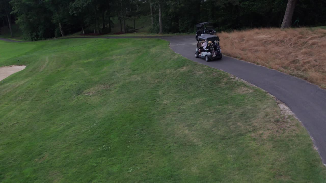 Un drone segue un gruppo di golfisti su golf cart mentre si dirigono alla buca successiva