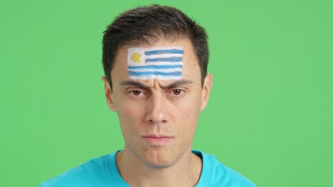 serious man with a uruguayan flag painted on the face