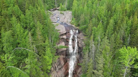 drone footage captures the solbergfossen waterfall surrounded by dense green forest in norway