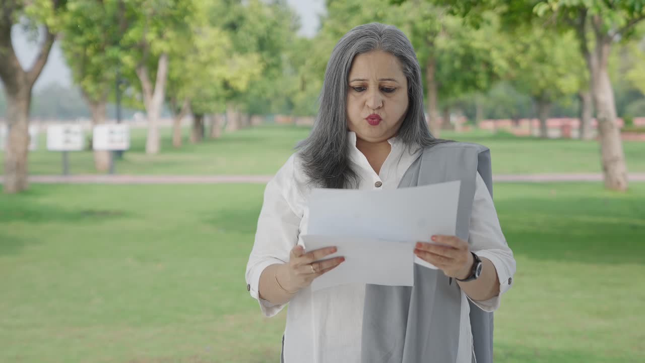 Anciana india confundida leyendo informes en el parque