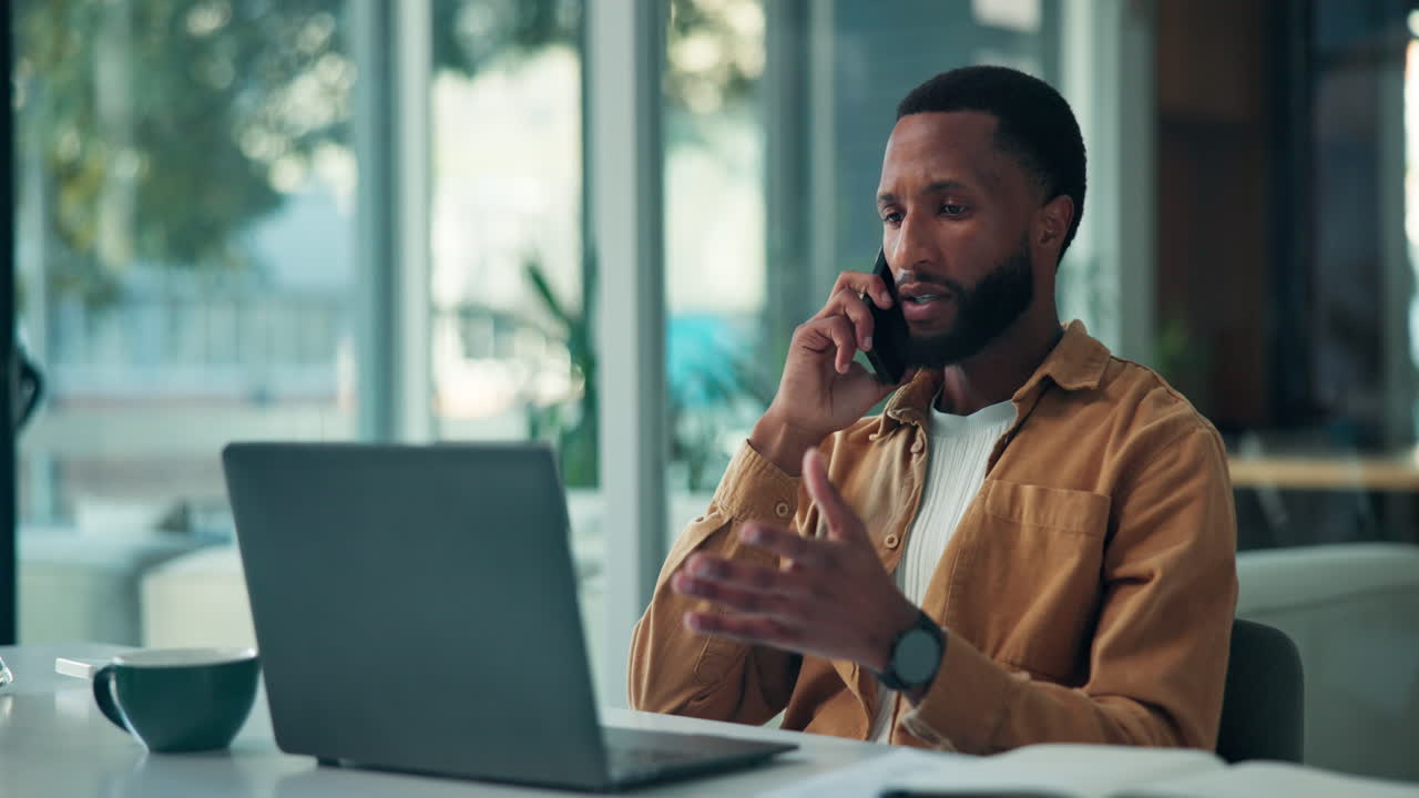 Man on Phone Working on Laptop