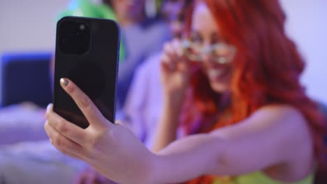 Foto-De-Estudio-De-Un-Grupo-De-Amigos-De-La-Generación-Z-Sentados-En-Un-Sofá-Posando-Para-Un-Selfie-Con-Un-Alienígena-De-Juguete-En-Un-Teléfono-Móvil-3