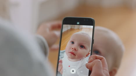 mother taking photo of baby using smartphone enjoying photographing cute toddler sharing motherhood lifestyle on social media