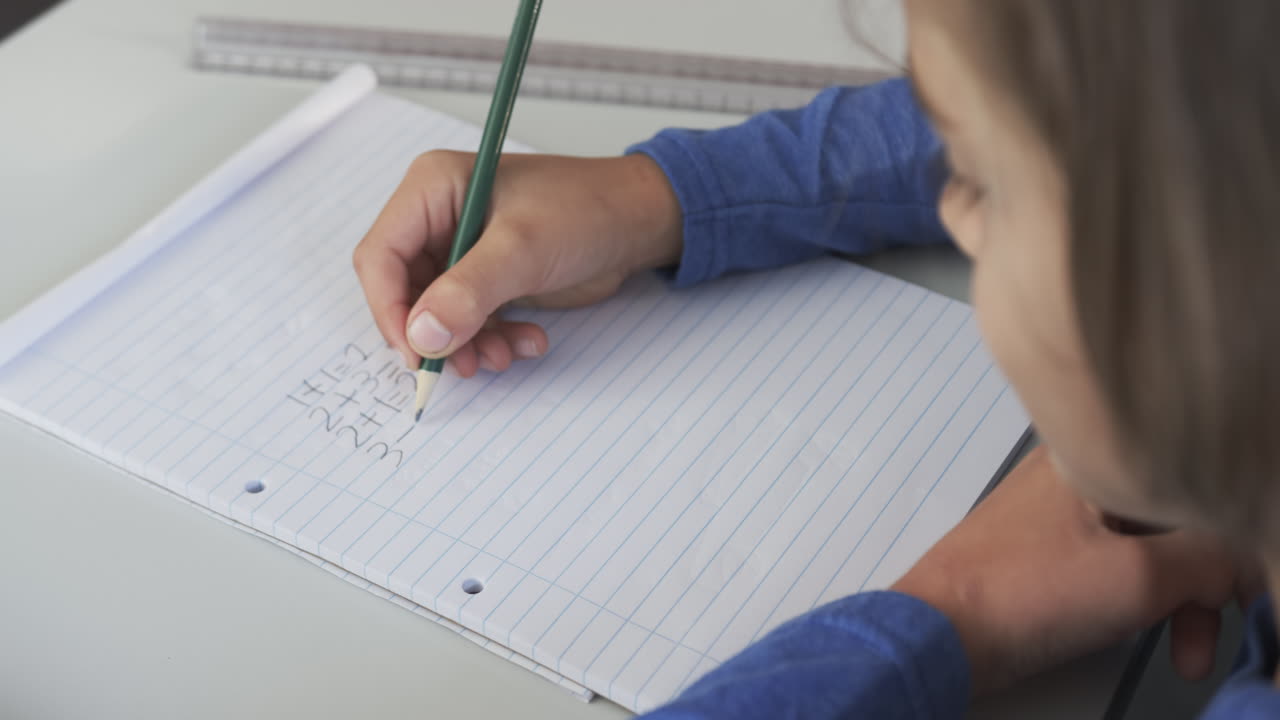 Practicing handwriting, child writing in notebook in school classroom