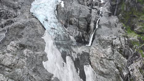 river stream of melted glacial ice is running down mountain cliffs beside tongue of boyabreen glacier in fjaerland norway - 60 fps