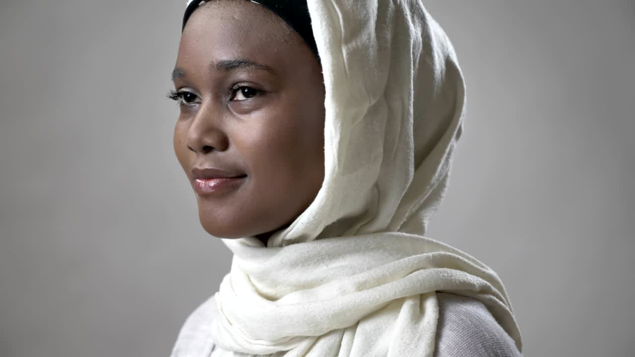 joven musulmana africana en hijab está girando la cabeza y mirando a la cámara, concepto religioso, fondo gris