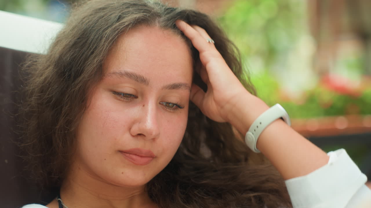 Donna rilassata che riposa. Donna con i capelli ricci che si gode il sole. Donna che si rilassa su una sdraio in mezzo a una lussureggiante vegetazione circostante. Donna serena con i capelli ricci che si immerge nell'atmosfera tranquilla del resort.
