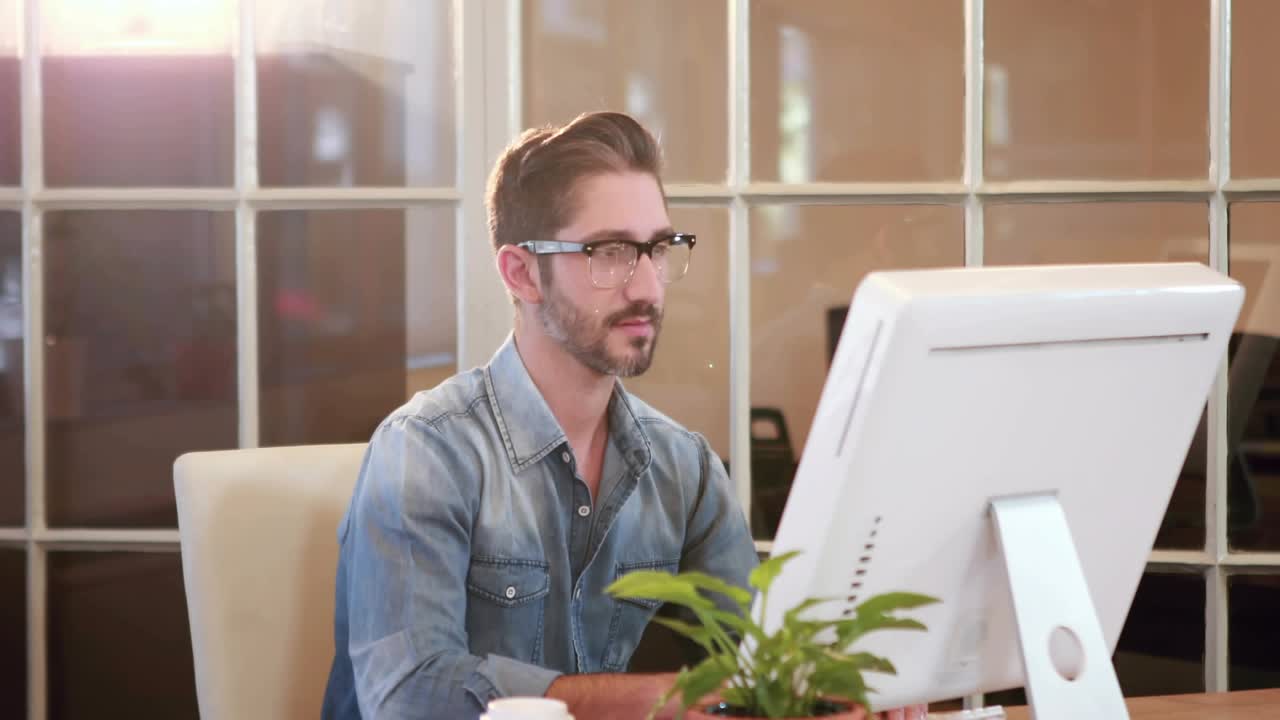 Man typing at desk, starting network icons flowing across monitor, showing business links