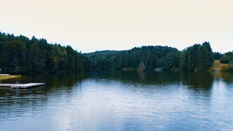 aerial-flying-low-over-a-lake-there-is-a-forest-and-a-small-pier