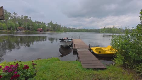 time lapse of a pedal boat and fishing boat tied to a dock on rainbow lake in the adirondacks in new york with dark clouds rapidly moving across the sky